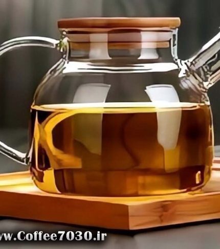 قوری پیرکس شفاف دارای دمنوش روی سینی چوبی