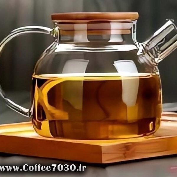 قوری پیرکس شفاف دارای دمنوش روی سینی چوبی